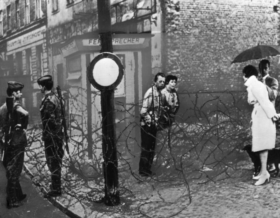 Một cặp Tây Đức và một cặp Đông Đức nói chuyện qua hàng rào kẽm gai dọc biên giới ở Berlin năm 1961. Bên trái là hai lính Đông Đức. (AP)