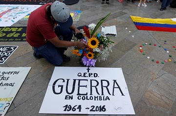 Một người đàn ông chào mừng hòa ước đình chiến lịch sử giữa chính phủ Colombia và phiến quân FARC tại Quảng trường Botero ở Medellin, Colombia, hôm 23-6-2016. Tấm biển ghi “Vĩnh biệt Chiến tranh ở Colombia 1964 - 2016”. (Ảnh: Fredy Builes/Reuters)