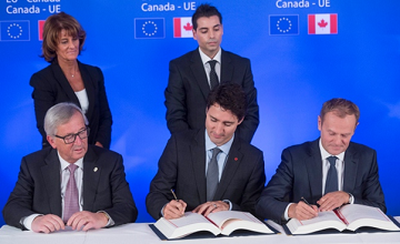 Thủ tướng Canada Justin Trudeau, ở giữa hàng trước, ký hiệp định CETA với Chủ tịch Ủy ban Châu Âu Jean-Claude Juncker, trái, và Chủ tịch Hội đồng Châu Âu Donald Tusk, phải, hôm 30-10 tại Brussels. (Ảnh: Thierry Monasse/Associated Press)